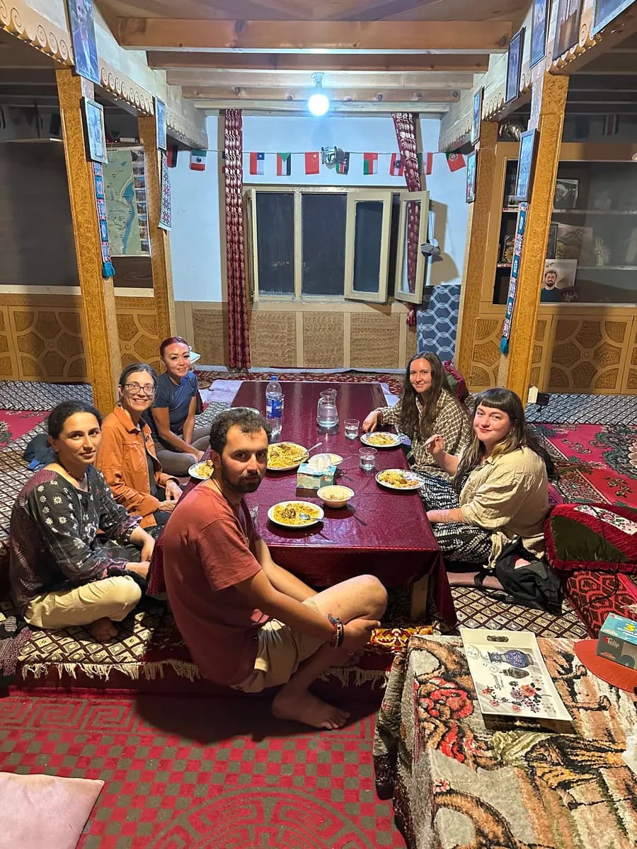 Guests and family sitting down to dinner together around the low table in our home in Ghulkin